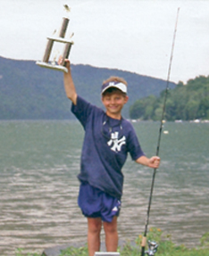 Colton Sposta (age 9) of Newtown, CT with his 1st place trophy for the biggest fish of the week (5.0 lbs).  This was Coltons first year at Bryans Fishing Camp.  August 20, 2004
